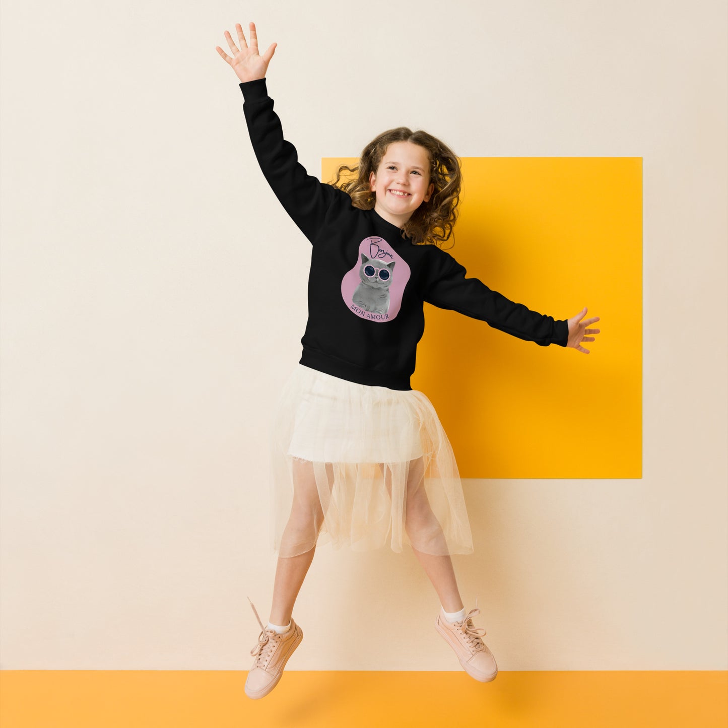 Happy girl jumping wearing Pet Treasures Studio Bonjour Mon Amour crewneck for kids in black with cat graphic