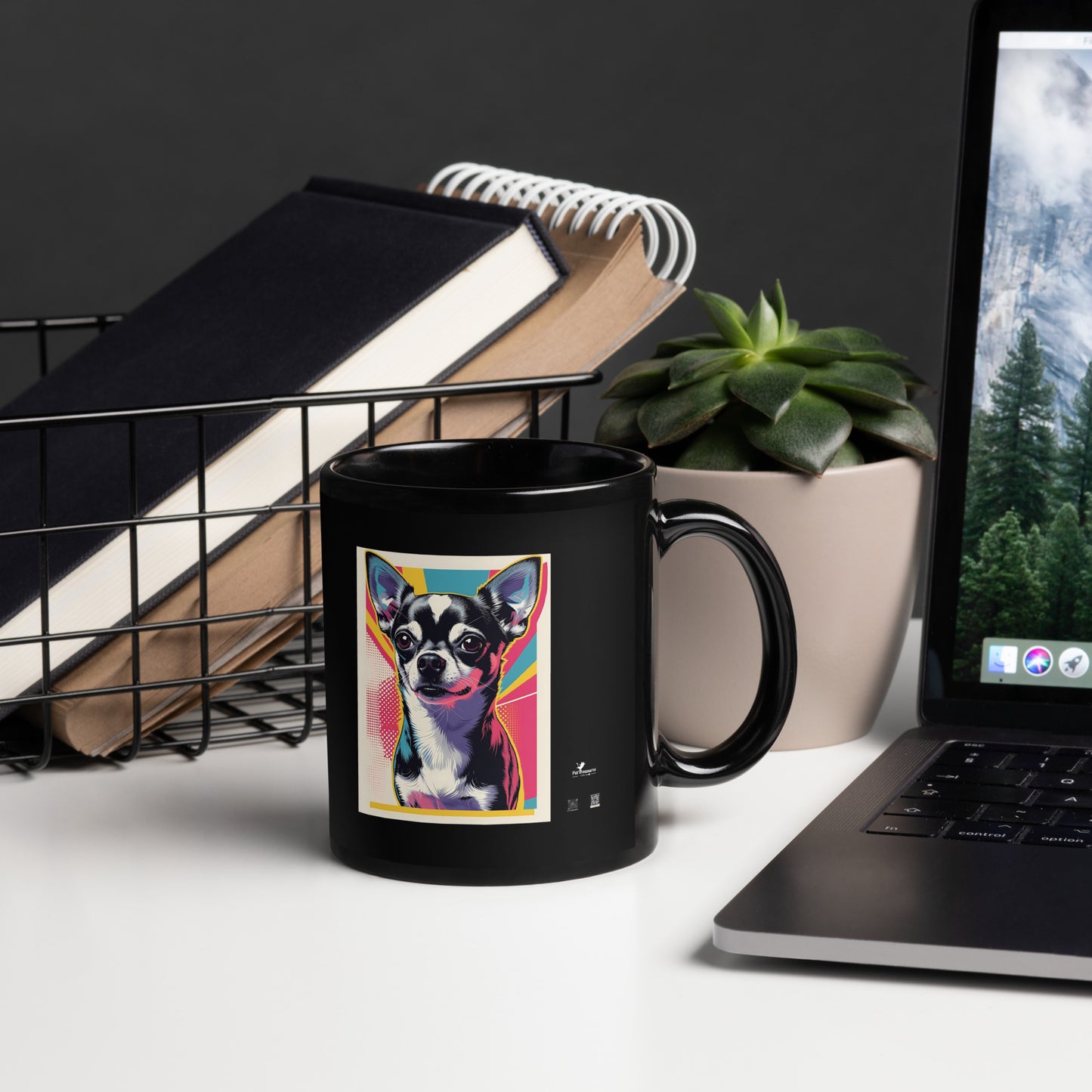 Black cute chihuahua coffee mug with colorful dog illustration next to laptop and plant