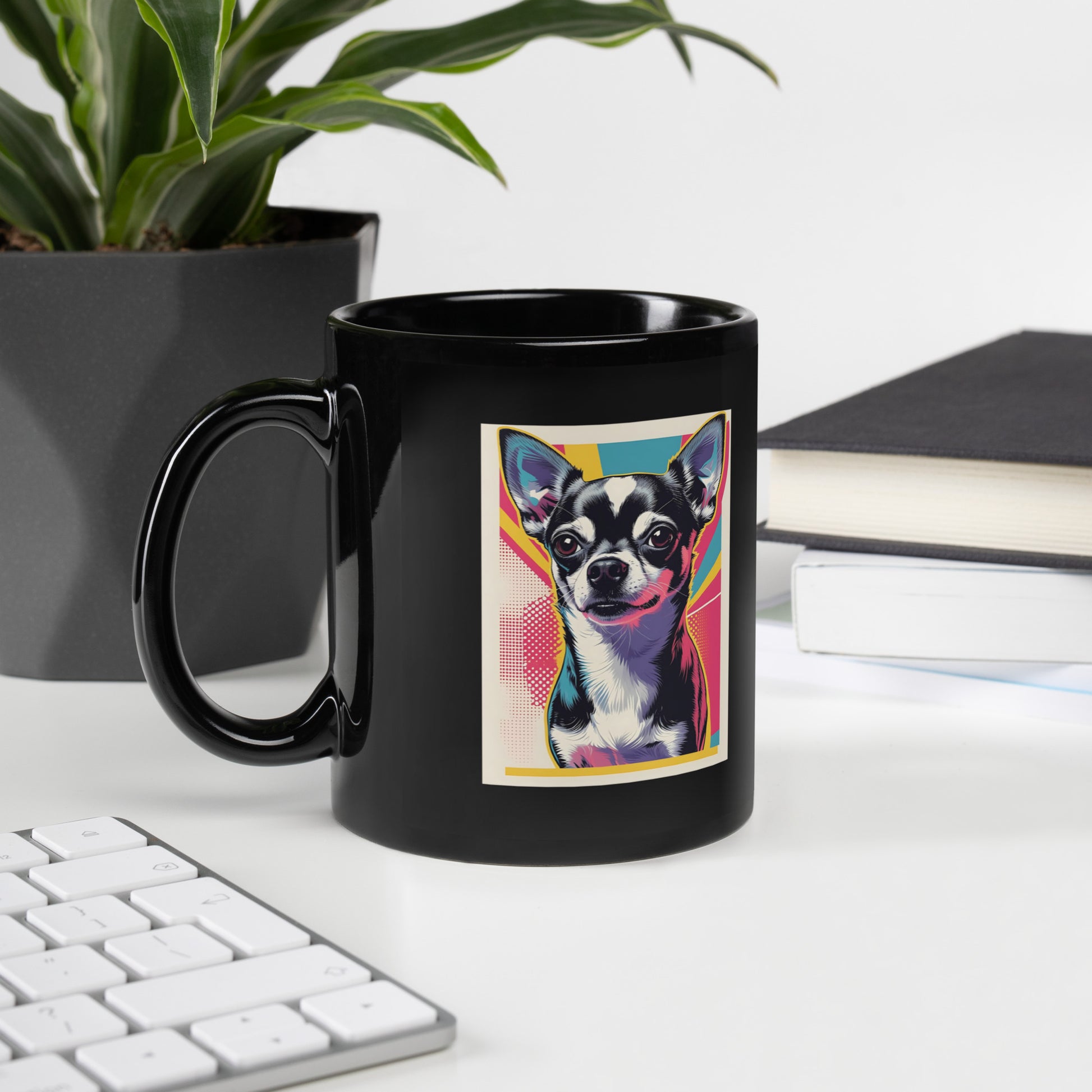 Black cute chihuahua coffee mug with colorful pop art design on a desk next to keyboard and plant